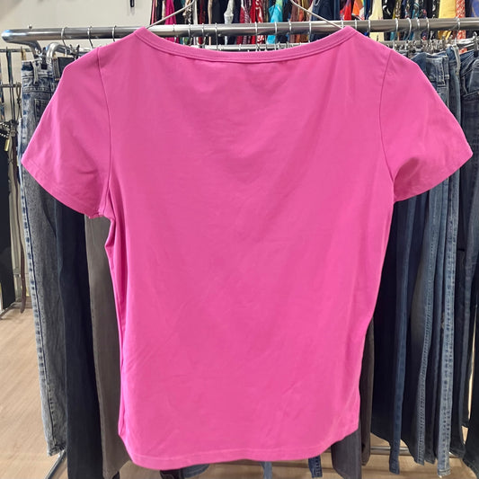 Pink t-shirt hanging on a rack with jeans in the background