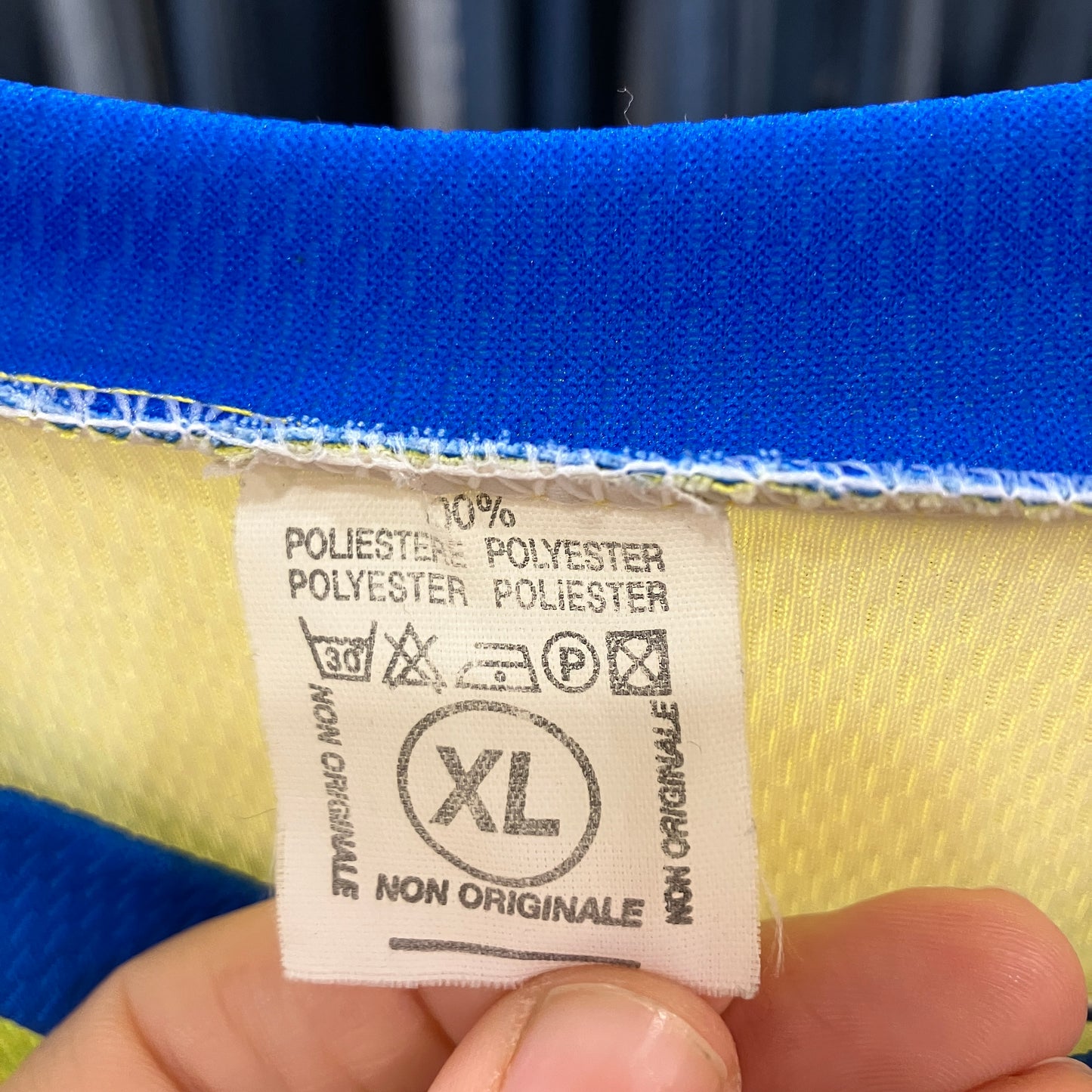 Clothing label on a blue and yellow fabric with care instructions