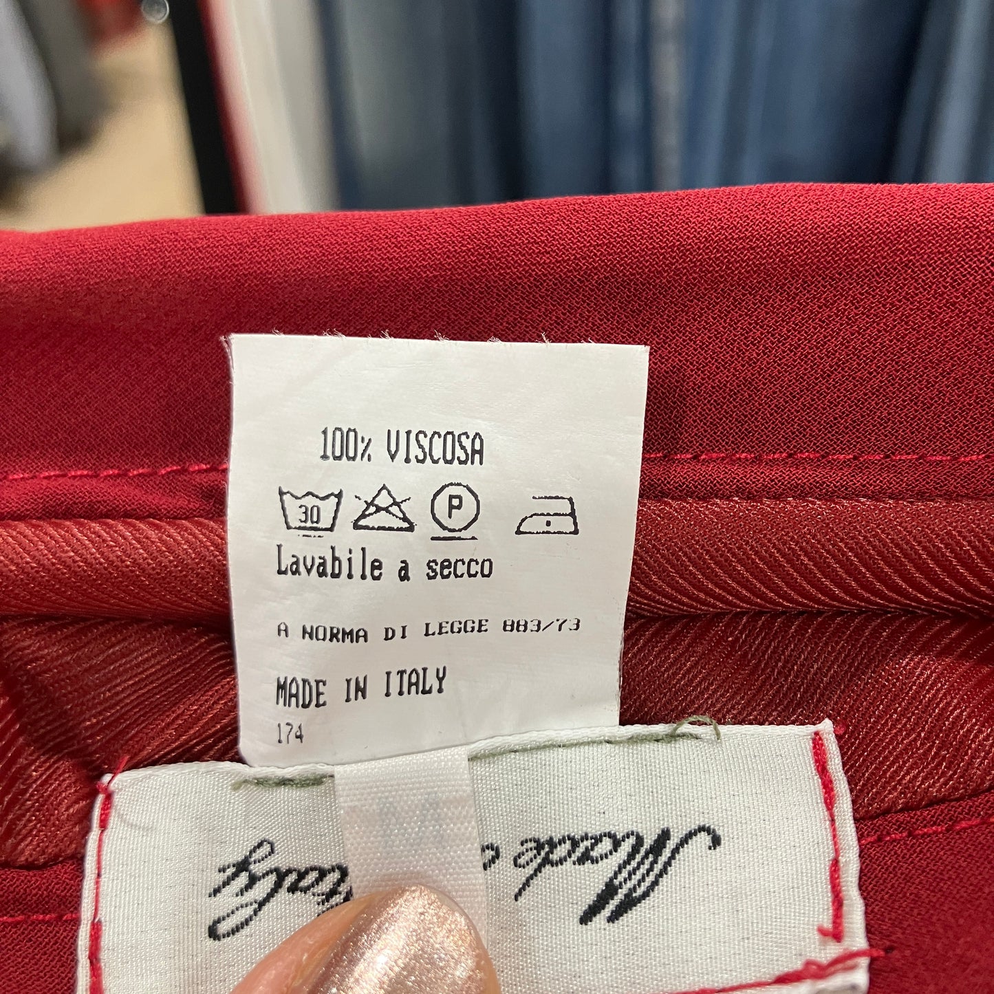 Fabric tag on red material with washing instructions and 'Made in Italy' text