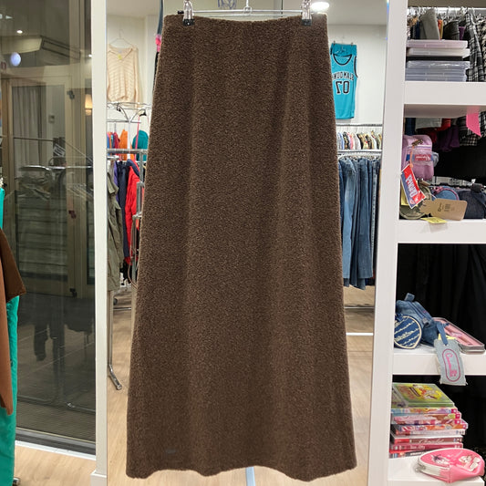 Brown skirt hanging in a store with shelves and clothing in the background