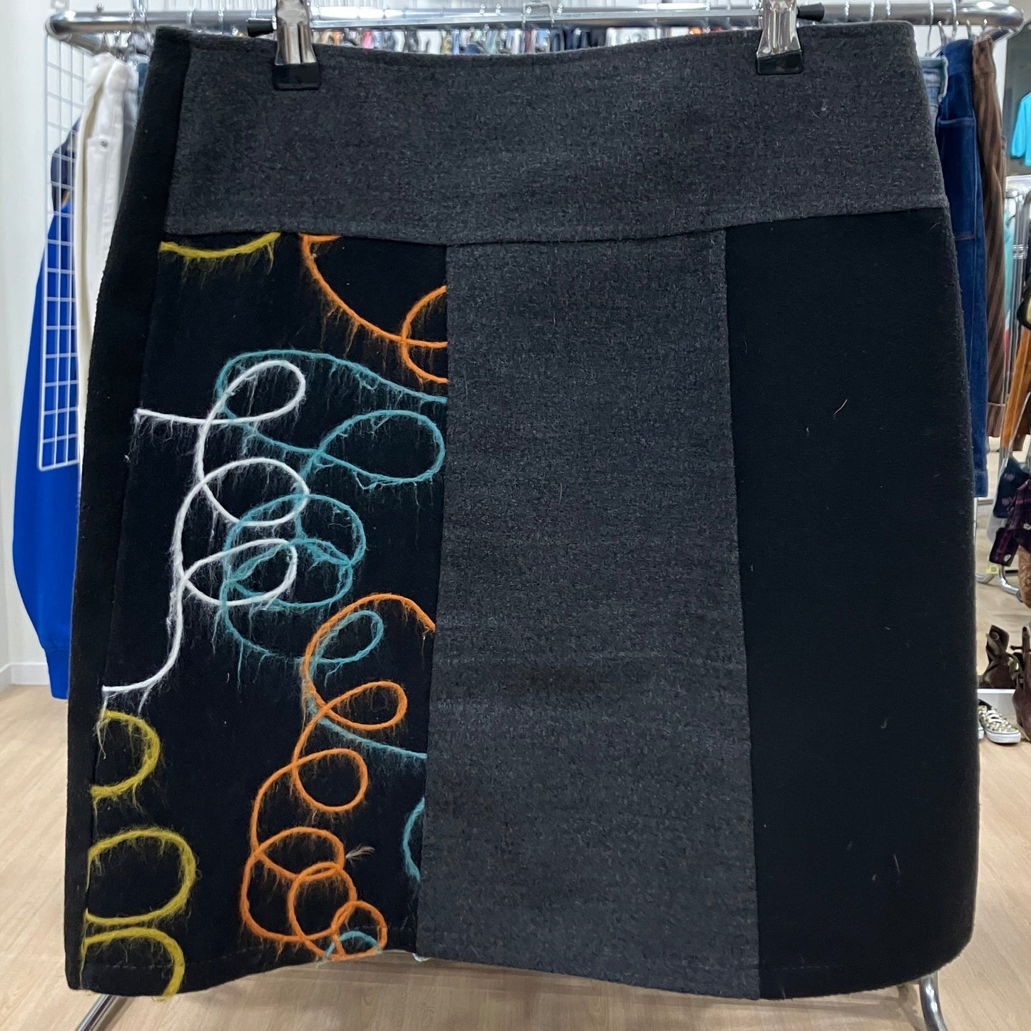 Gray skirt with colorful designs on a clothing rack in a store