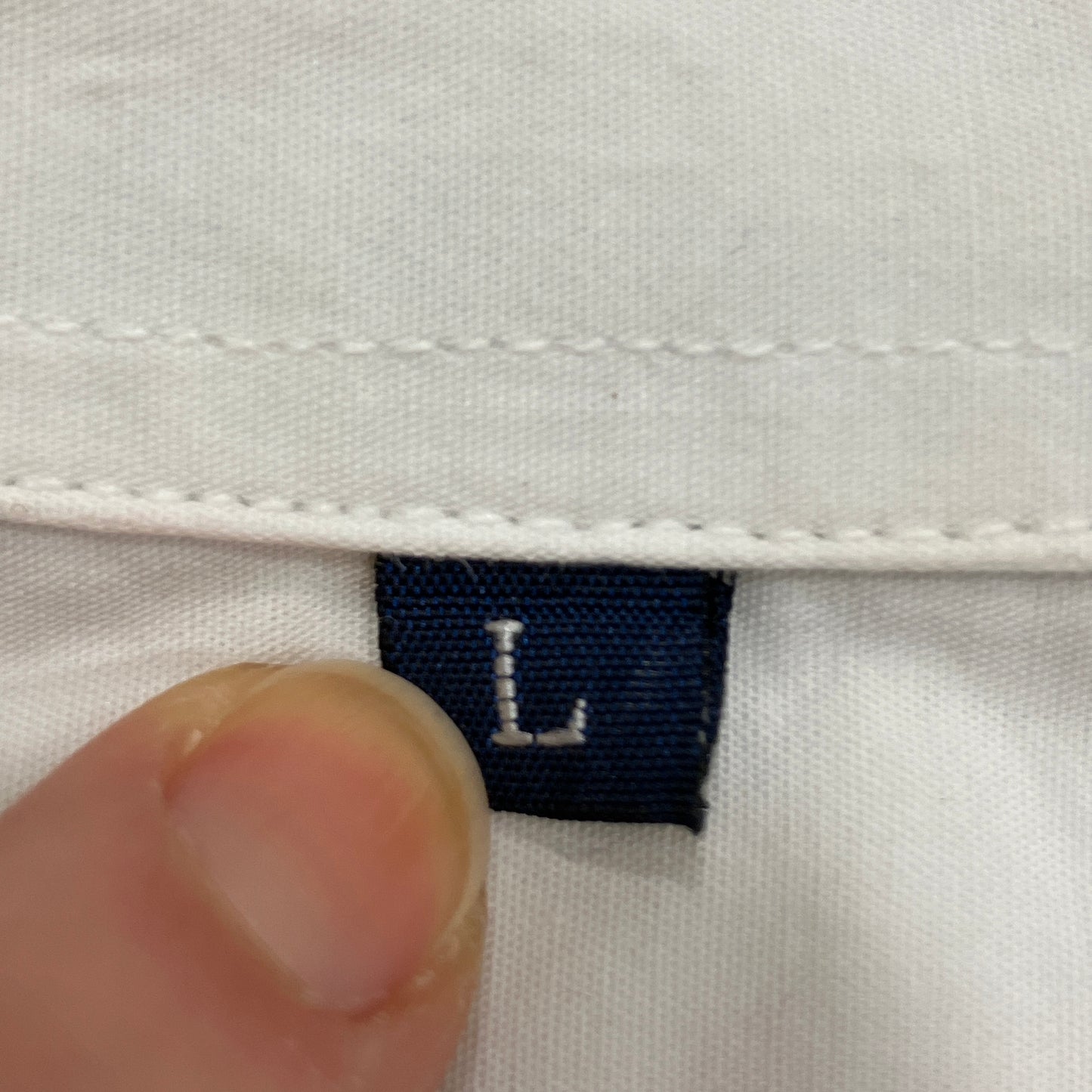Size label 'L' on a white shirt with a hand for scale
