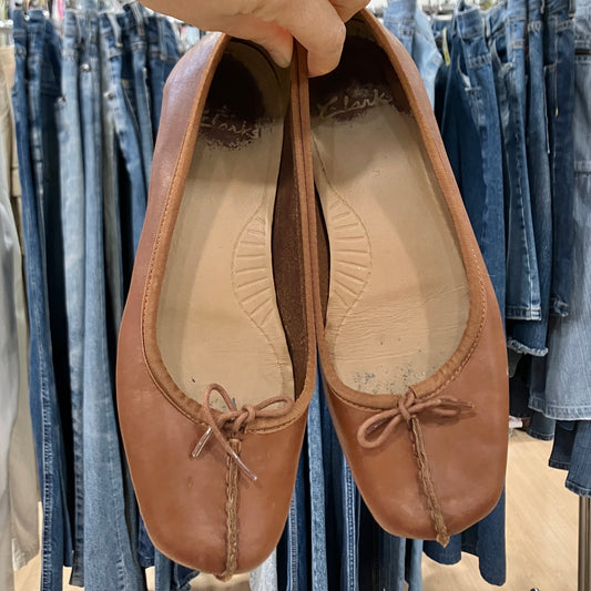 Brown leather shoes held in front of denim clothing racks