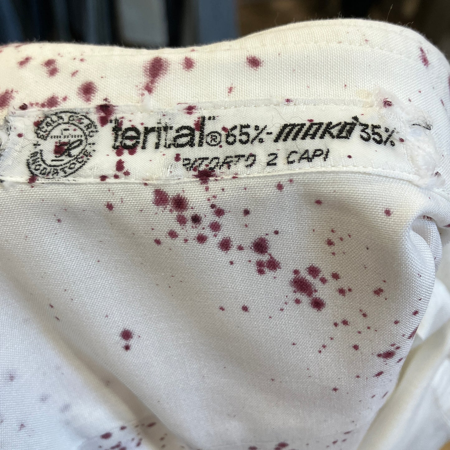 Close-up of a fabric label with text and specks on a white background