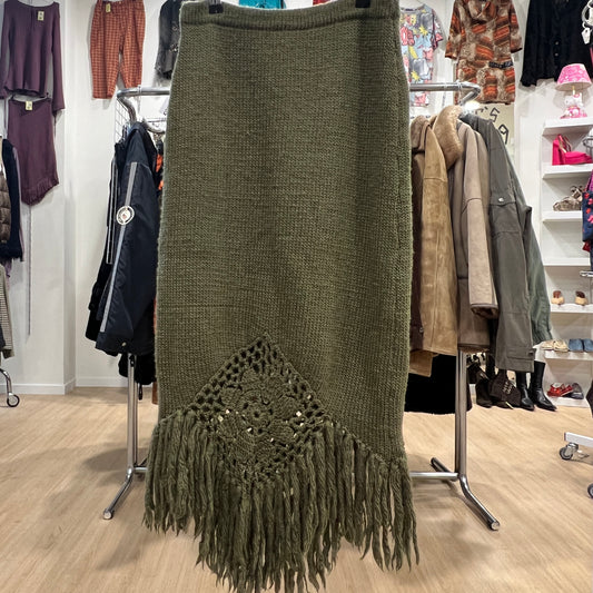 Green knitted skirt with fringe details in a clothing store setting