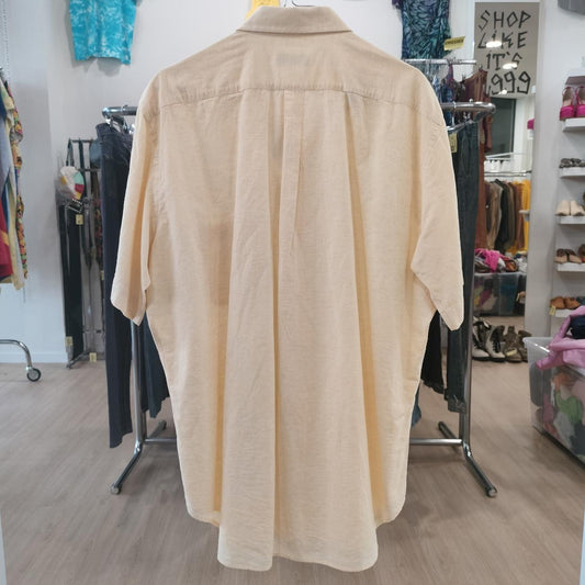 Beige shirt on a mannequin in a store setting with various items in the background