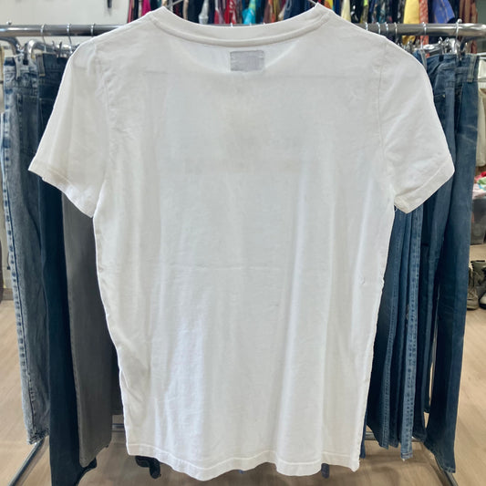 White t-shirt hanging on a rack with jeans in the background