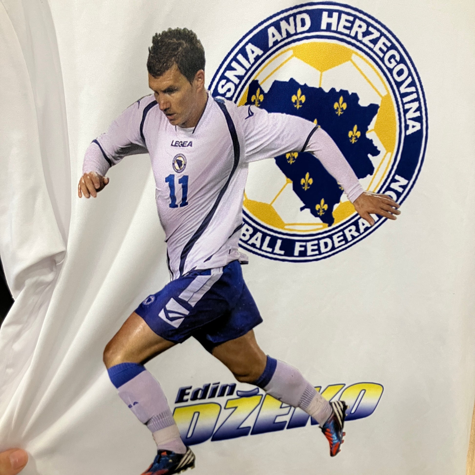 Soccer player in a white and blue uniform with a logo in the background