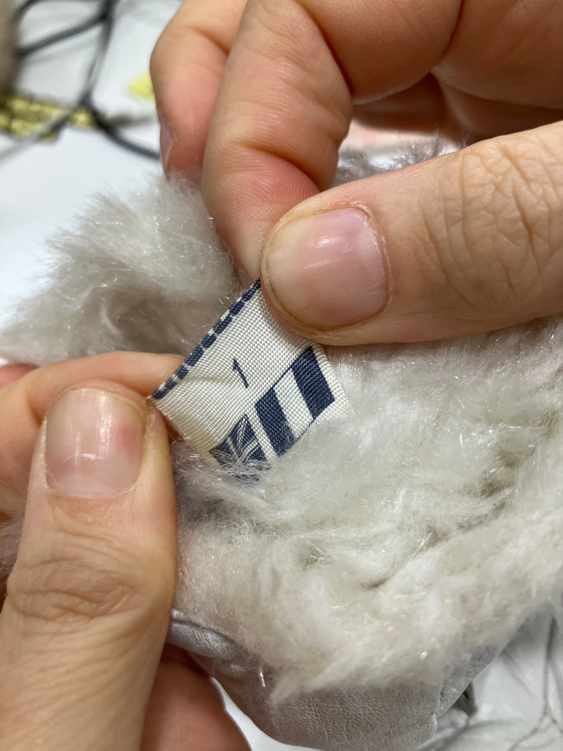 Close-up of hands holding a label on a fluffy white product