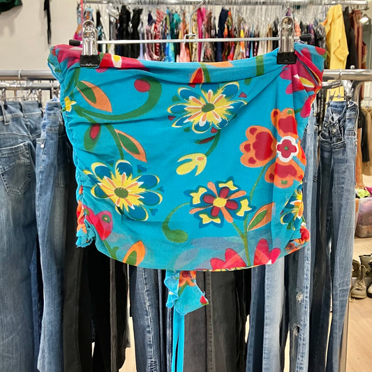 Blue floral off-shoulder blouse with ruffle detailing hanging on a rack inside a clothing store