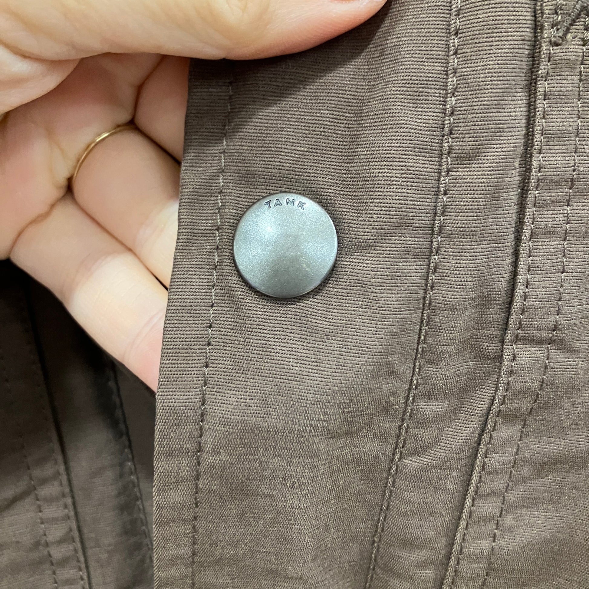 Close-up of a button on a brown fabric with a hand holding it