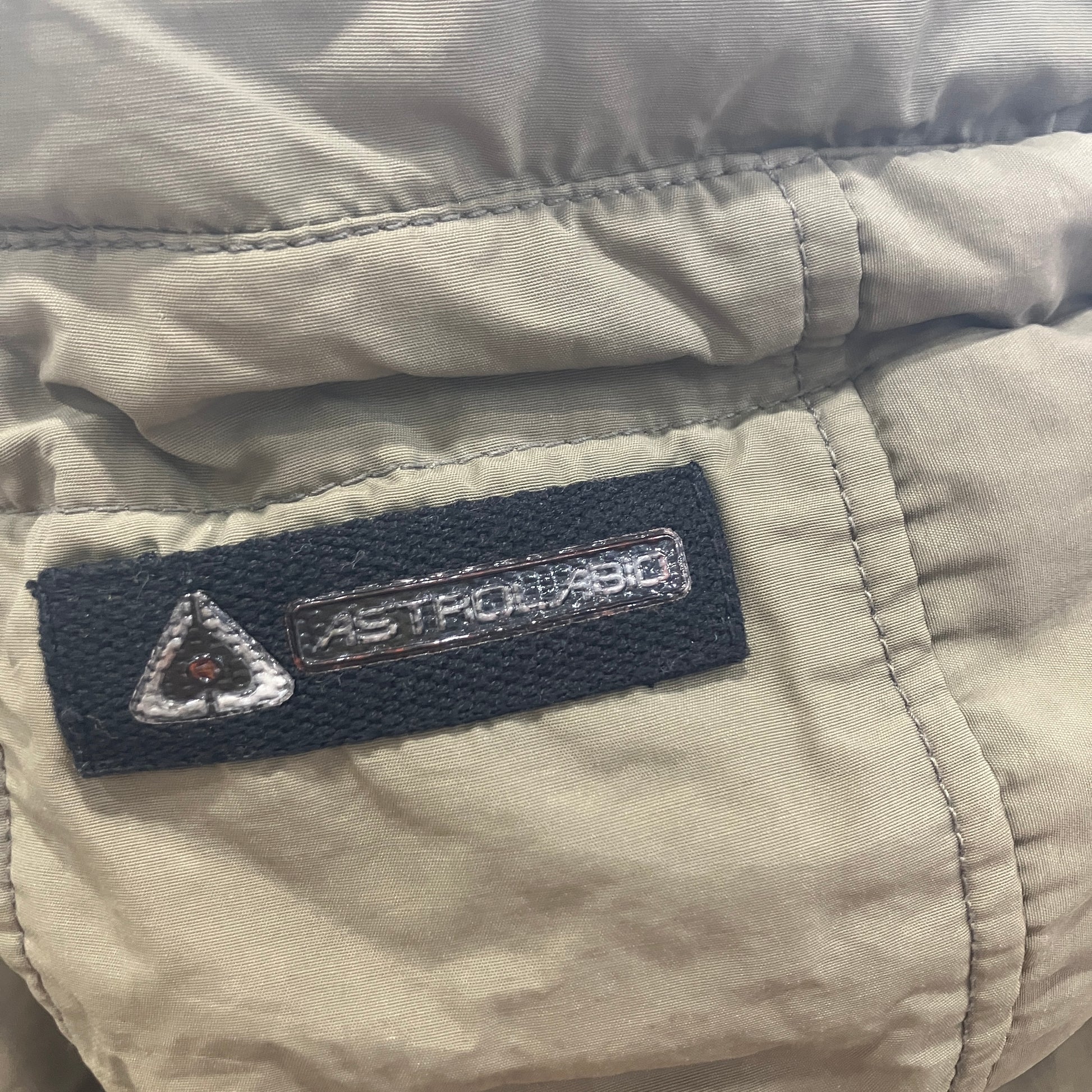Close-up of a label on a beige jacket with 'ASTROTECH' branding
