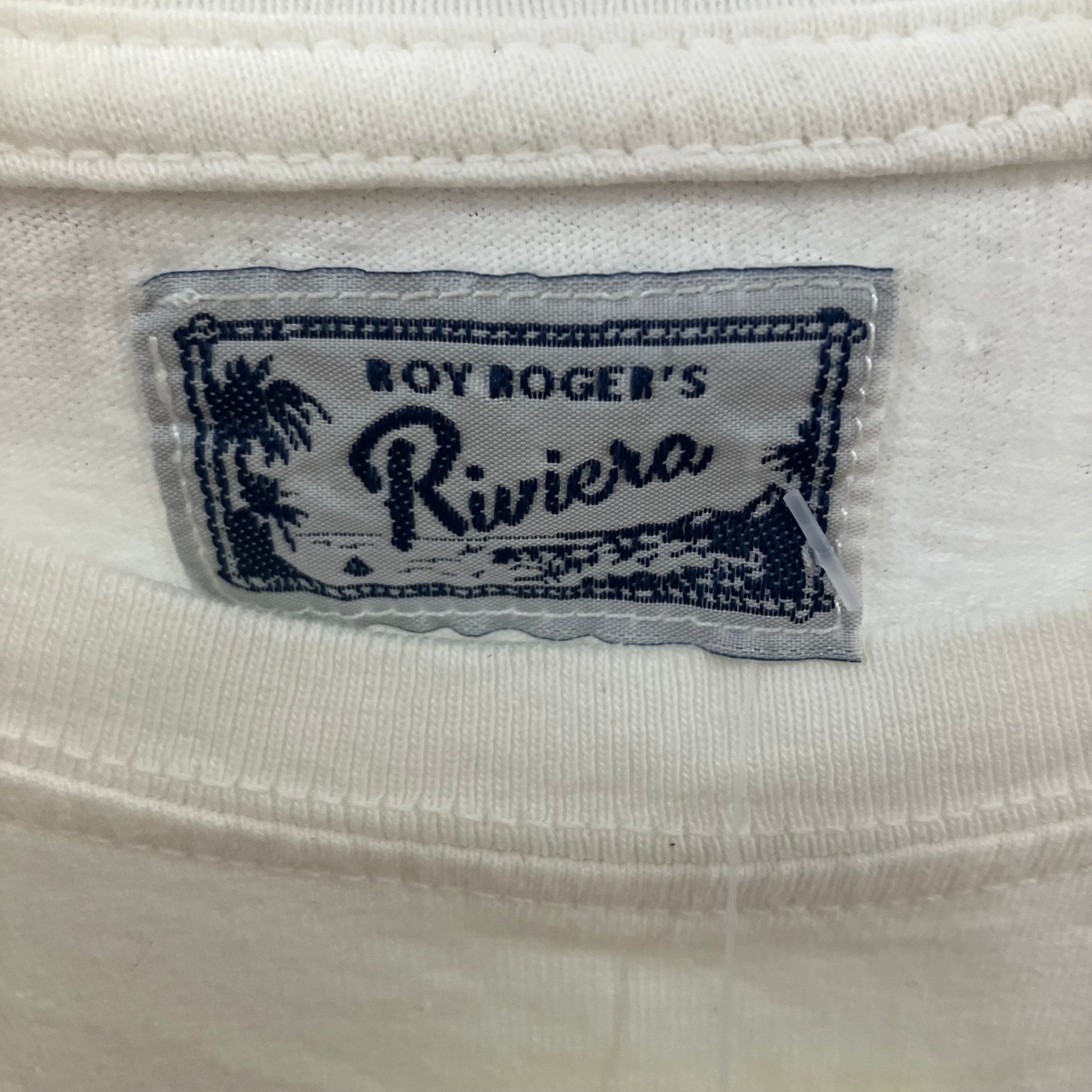 Close-up of a 'Boy Roger's Riviera' label on a white fabric background