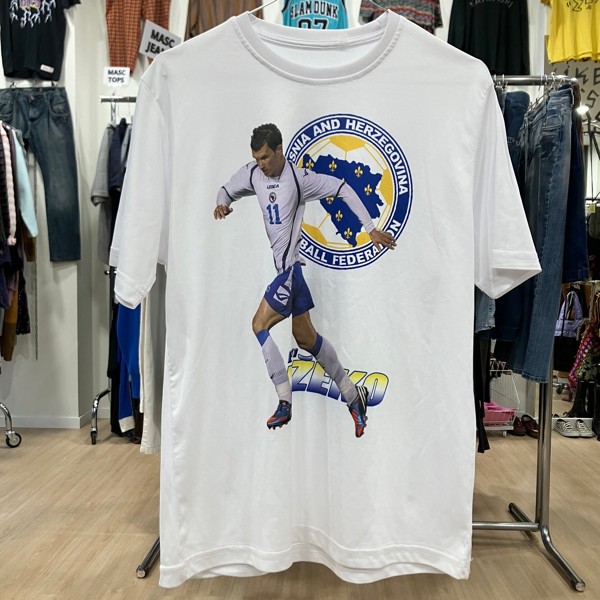 White t-shirt with a soccer player graphic and 'Sarajevo and Herzegovina' text in a clothing store