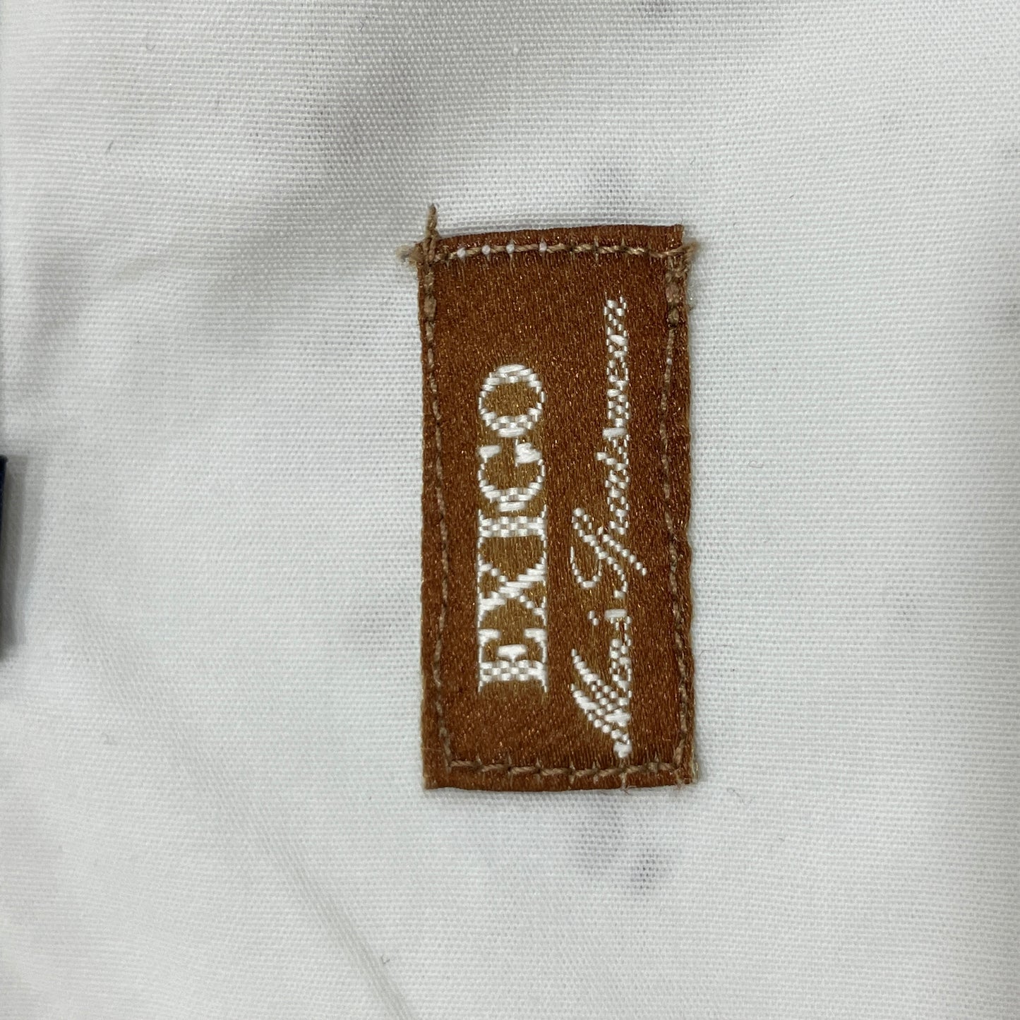 Close-up of a brown fabric label with 'EXIGO' text on a white background