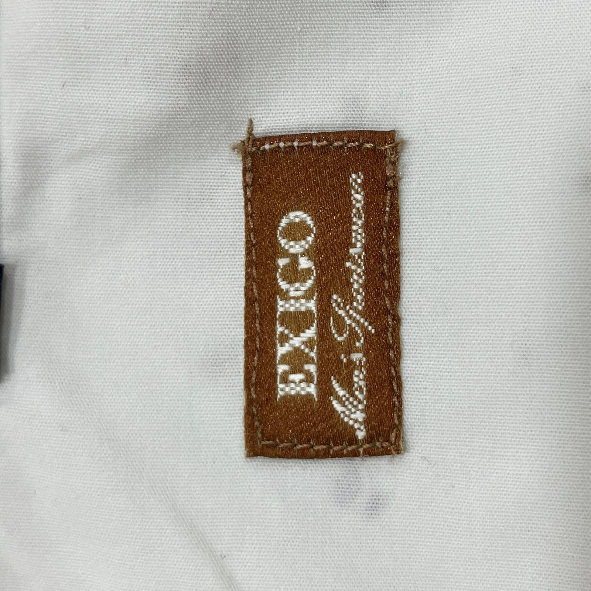 Close-up of a brown fabric label with 'EXIGO' text on a white background