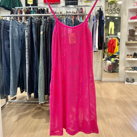 Pink lace dress hanging on a rack in a store with jeans and other clothing in the background