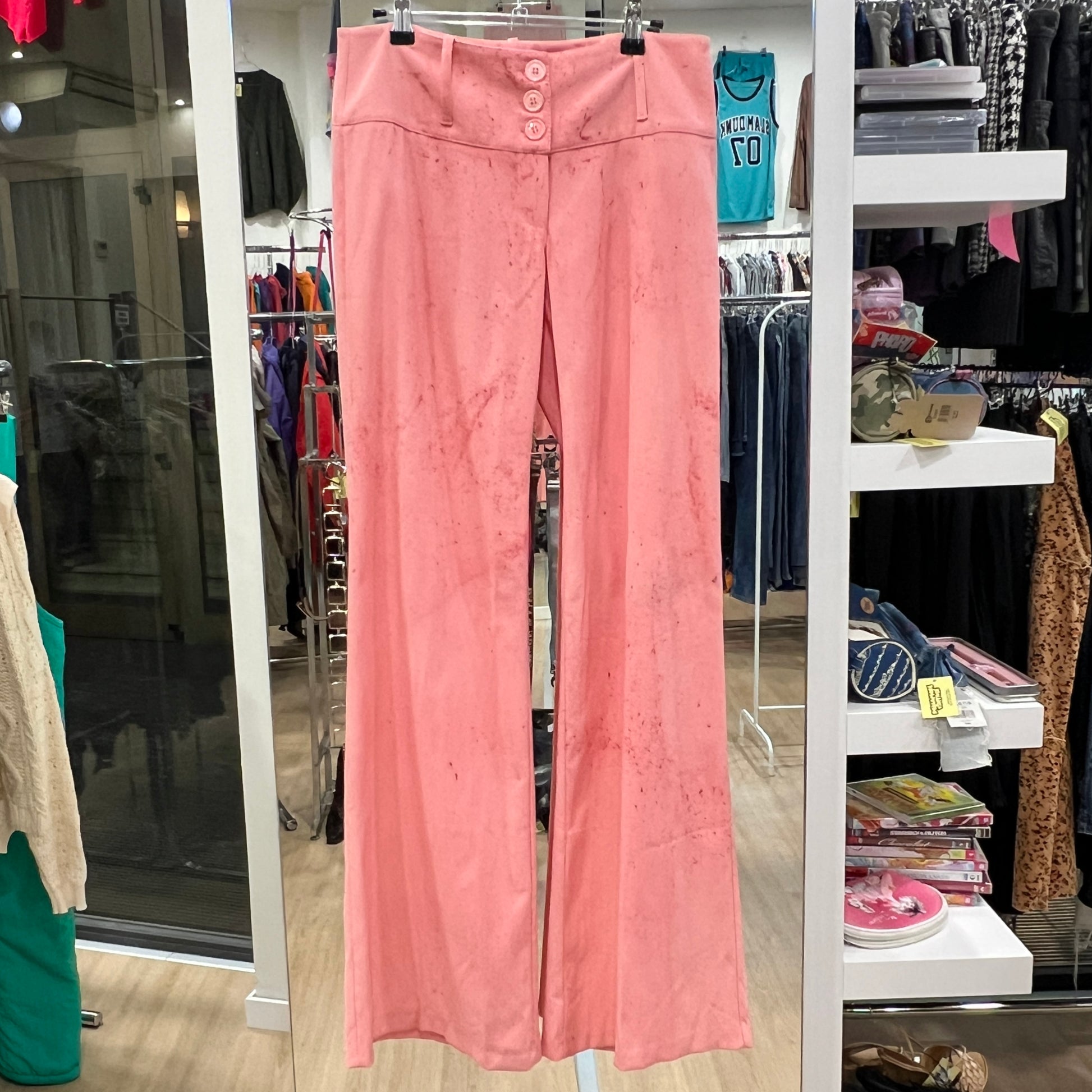 Pink pants hanging in a store with various clothing items in the background