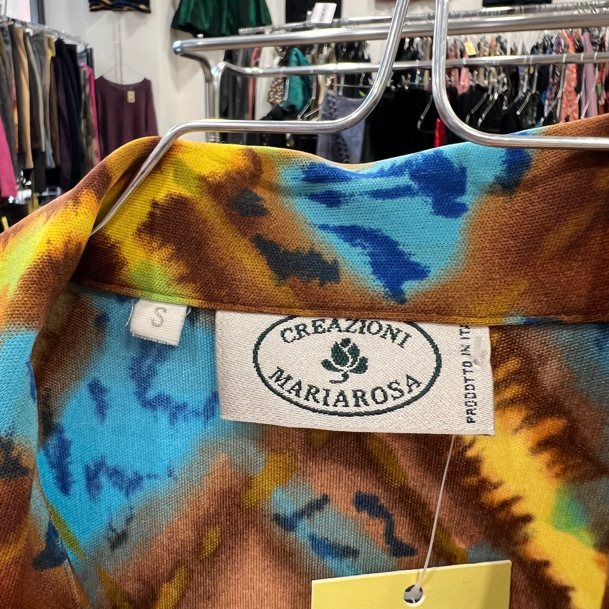 Colorful tie-dye shirt with a brand label on a hanger in a store setting