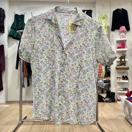 Floral patterned shirt on a hanger in a store setting with other clothing items