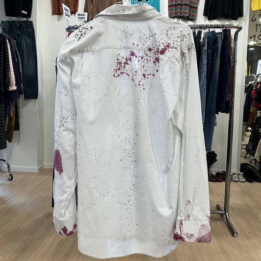 White jacket with red splatter stains on a hanger in a clothing store