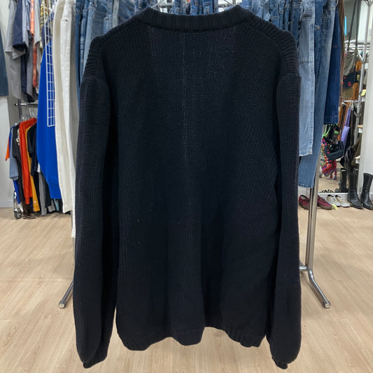 Black sweater hanging on a rack in a store setting