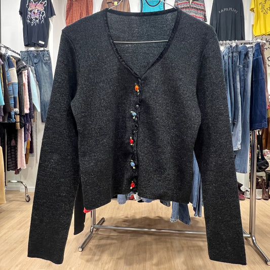 Dark gray cardigan with colorful buttons on a clothing rack in a store