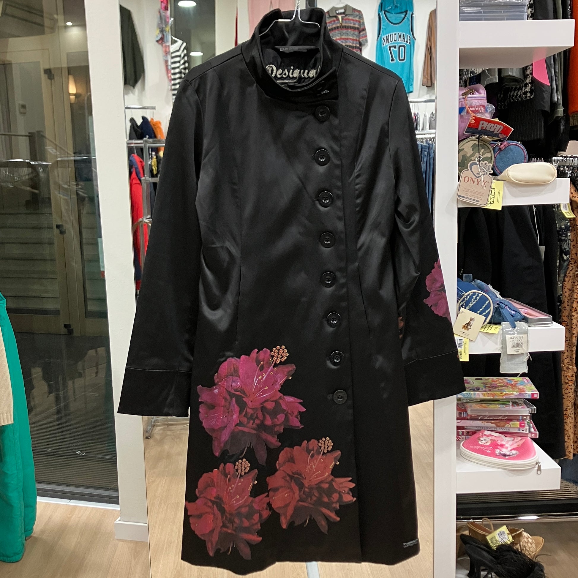 Black coat with floral embroidery in a store setting