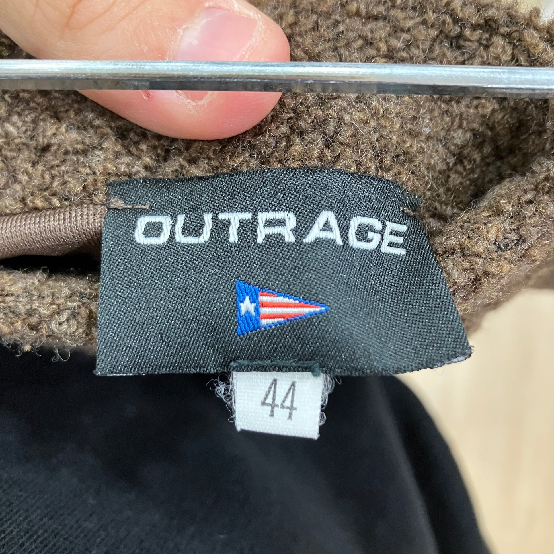 Label with 'OUTRAGE' text and a flag design on a textured fabric background