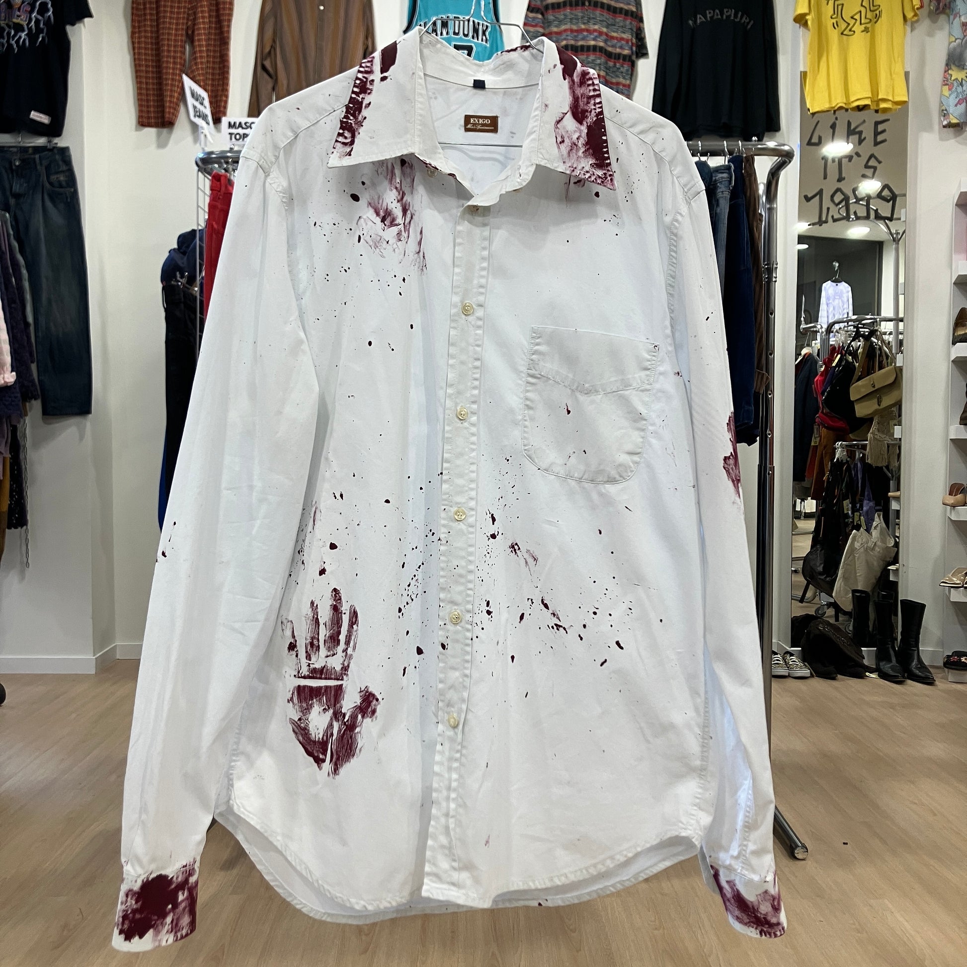 White shirt with red handprint and bloodstains on a rack in a store
