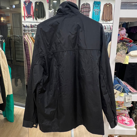 Black jacket displayed in a store with clothing racks in the background