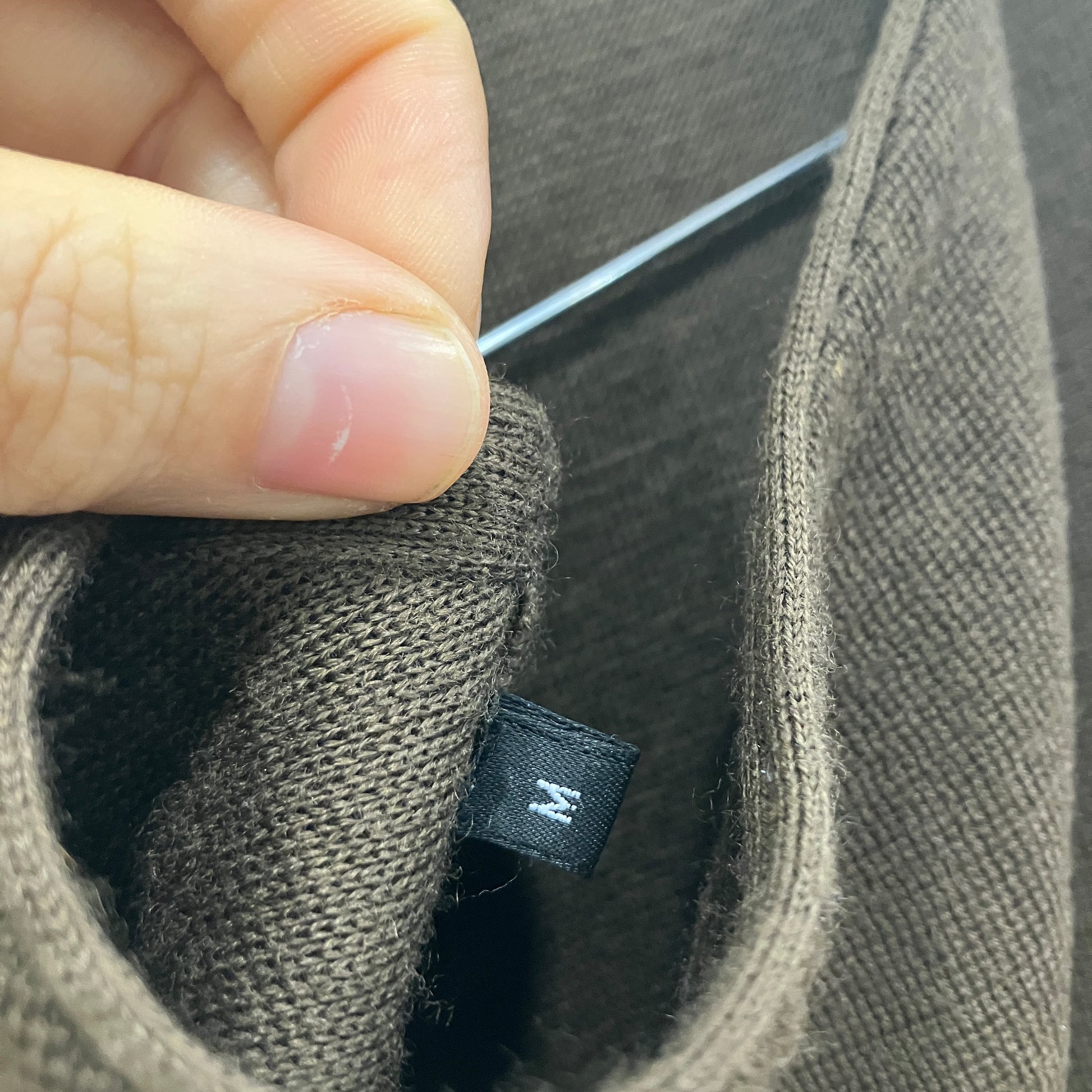 Close-up of a brown fabric item with a brand label, held by a hand