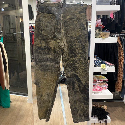 Distressed green-brown jeans hanging on a rack inside a clothing store