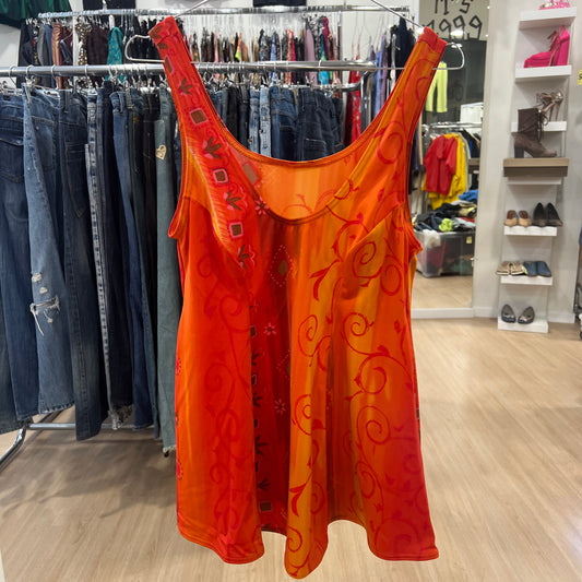 Orange sleeveless top with floral patterns hanging in a store setting