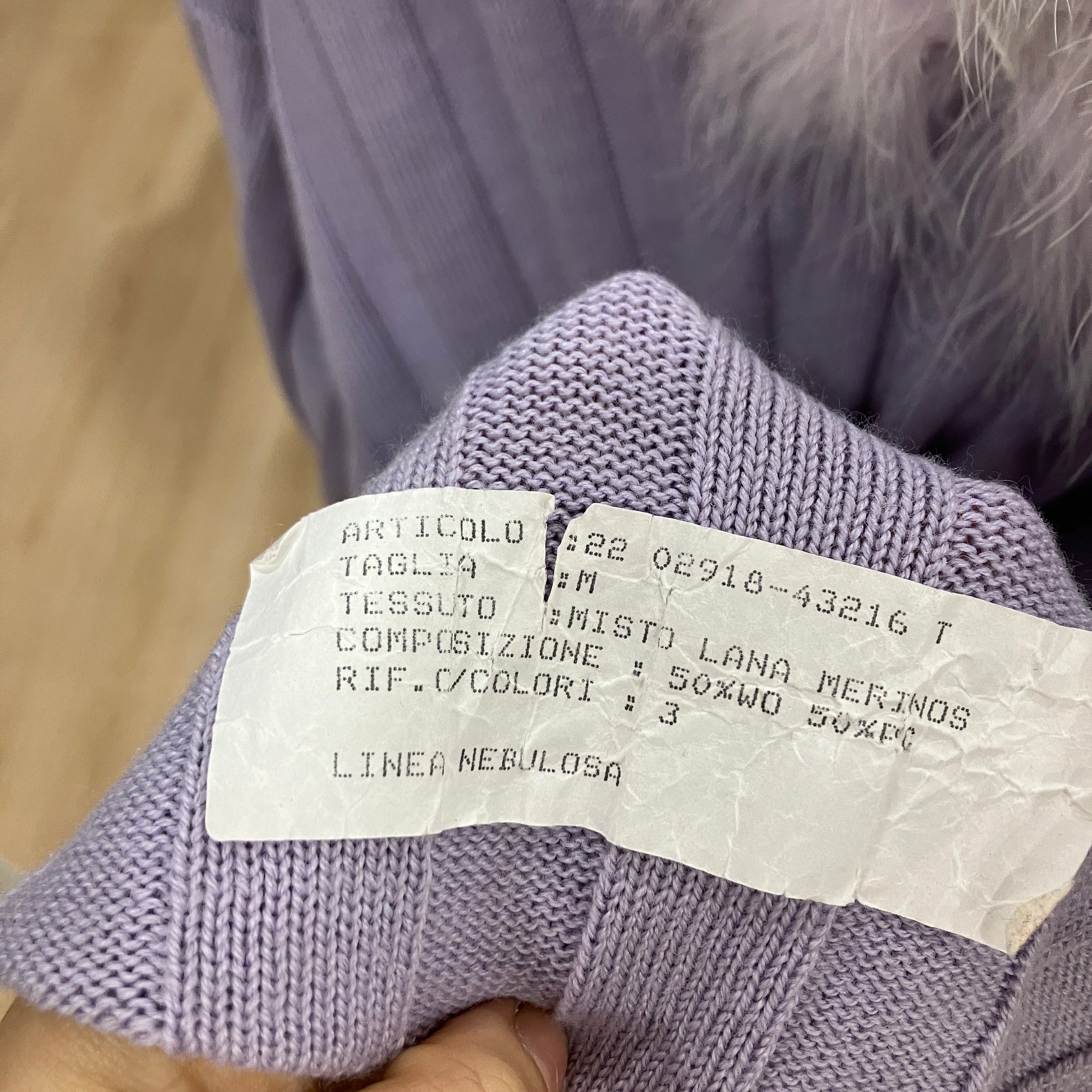 Close-up of a label on a purple knitted garment with text details