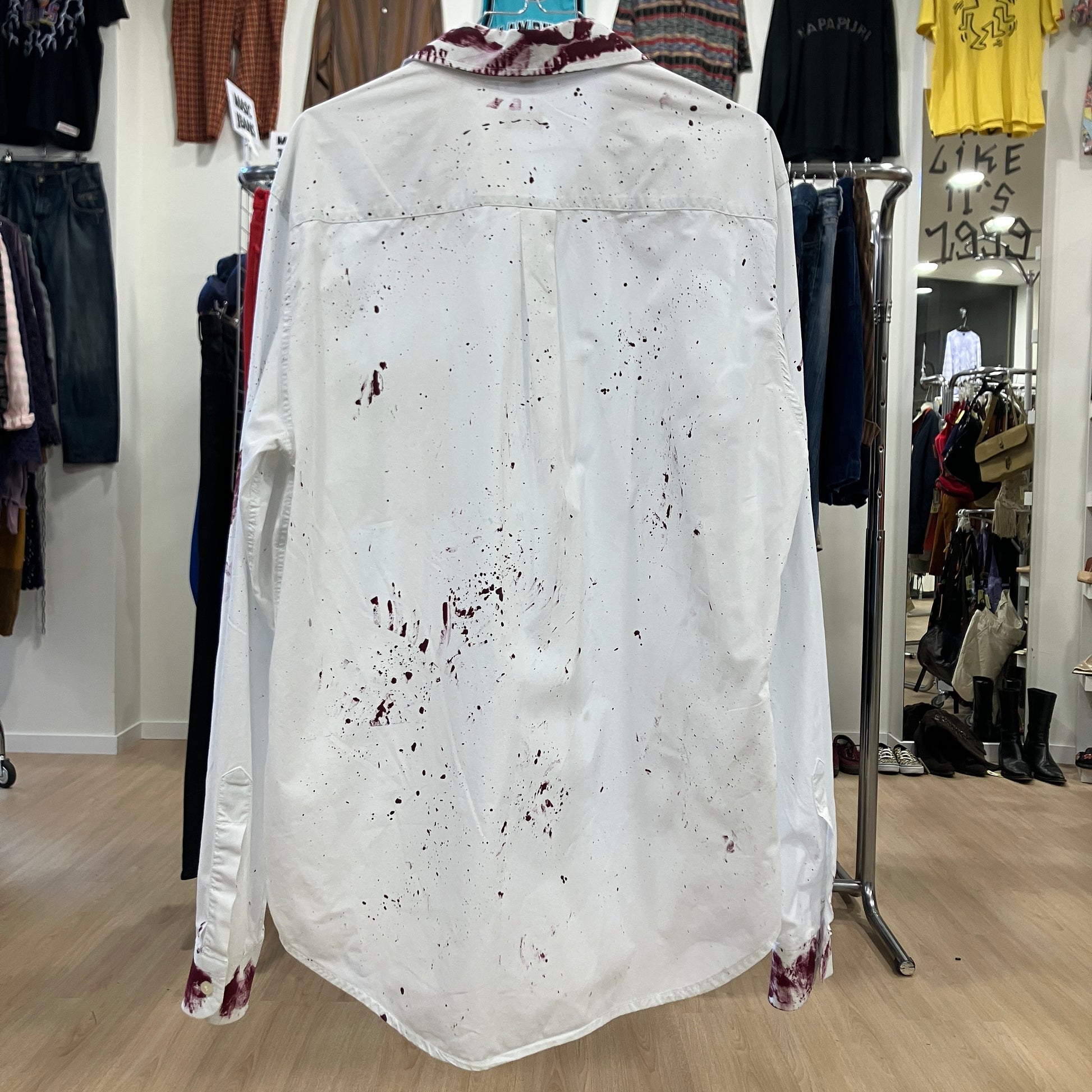 White shirt with red stains on a hanger in a clothing store