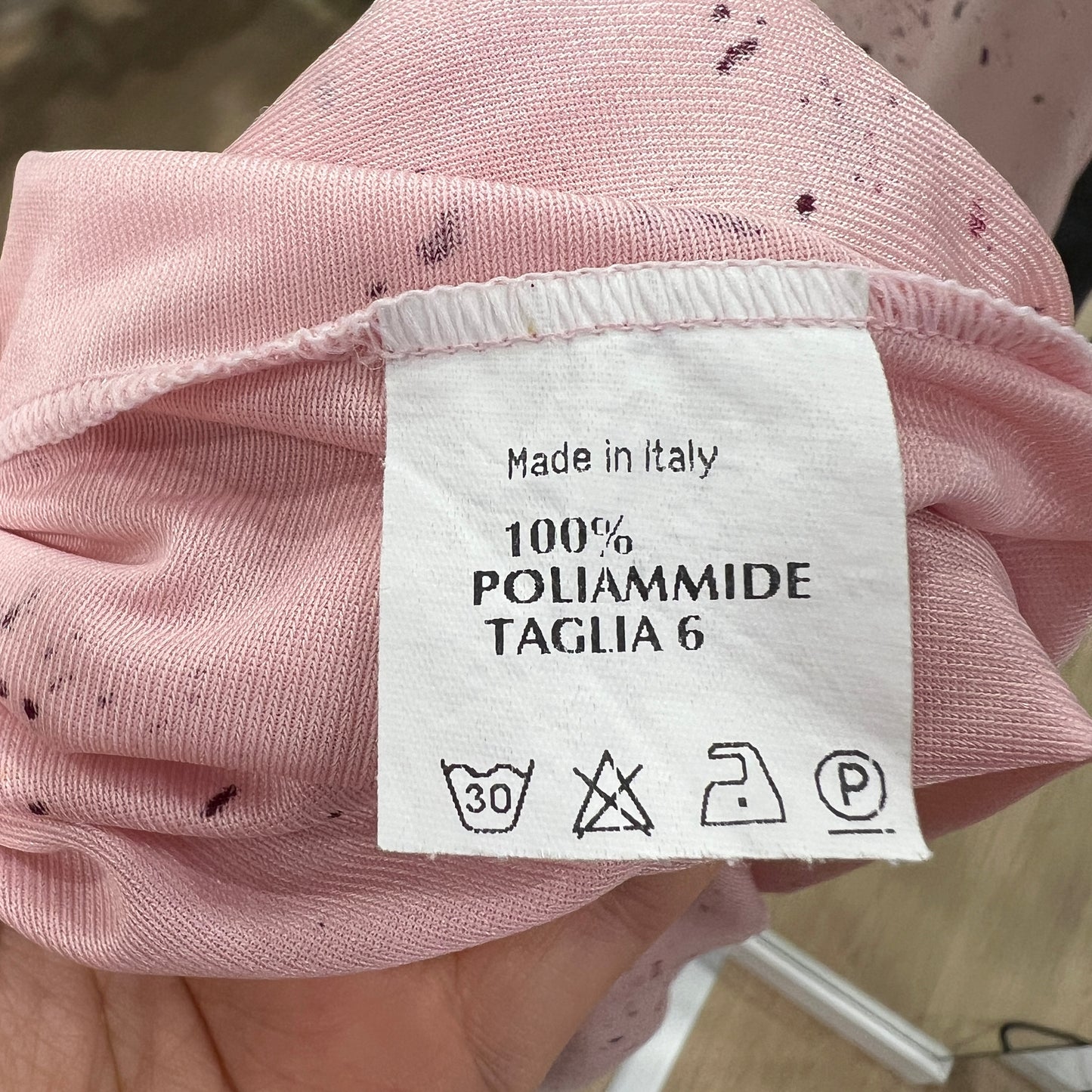 Pink fabric with a clothing label indicating 'Made in Italy' and material details