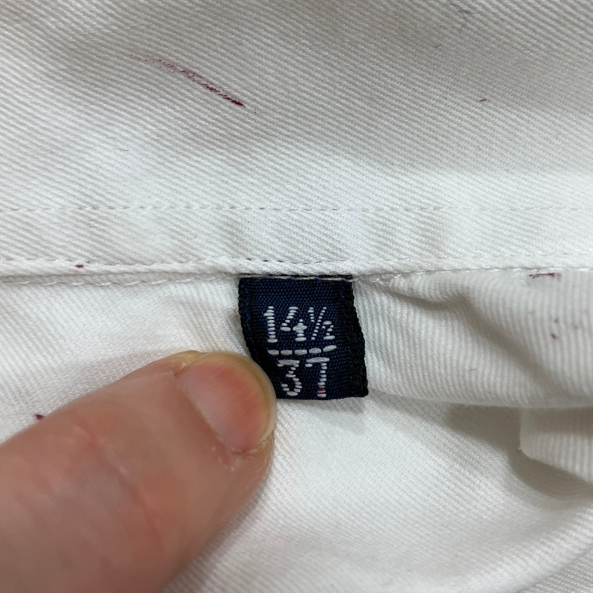 Clothing tag on a white fabric with a hand holding it