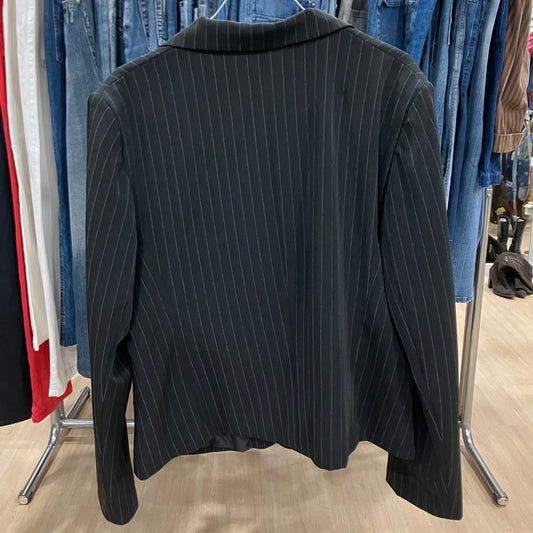 Black pinstripe blazer on a rack with other clothing in the background