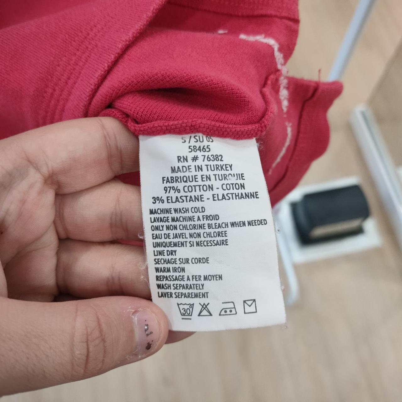 Clothing label held by a hand with a blurred background