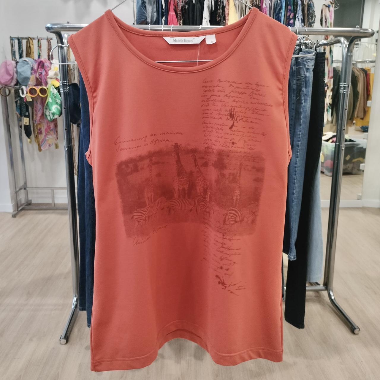 Orange sleeveless shirt with graphic design on a clothing rack