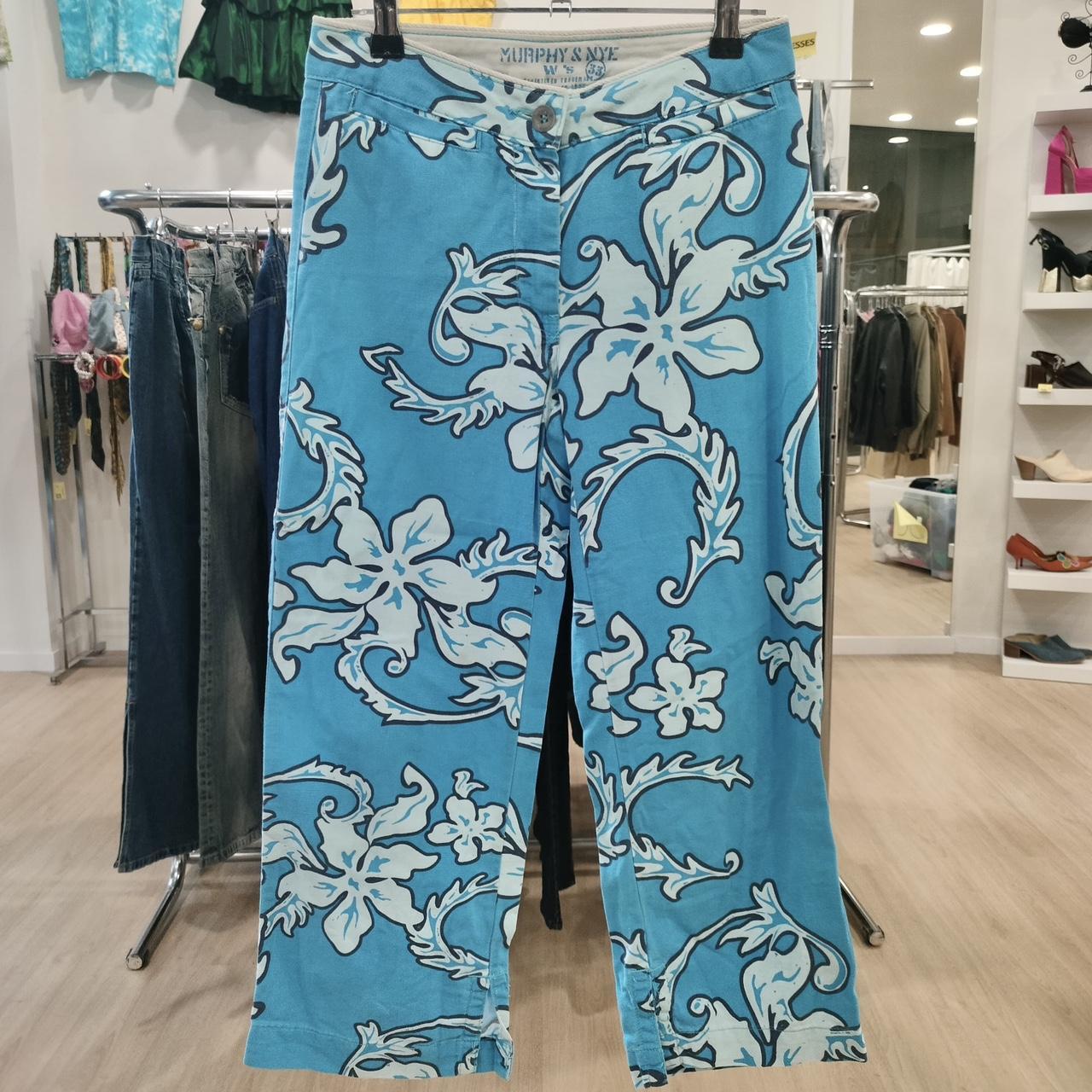 Blue floral-patterned pants hanging on a rack in a store setting