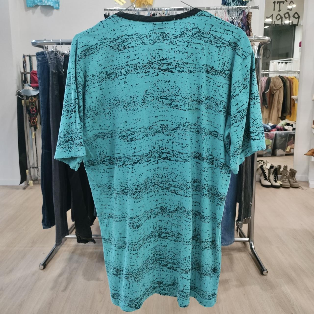 Teal patterned dress hanging on a rack in a store setting