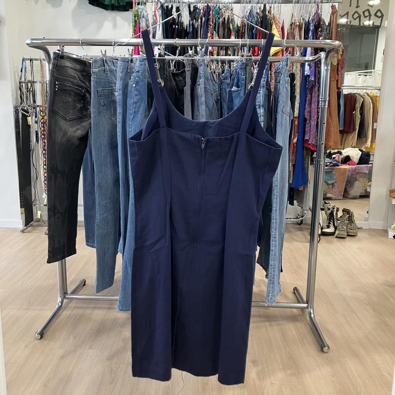 Navy blue dress on a clothing rack with jeans in a store setting