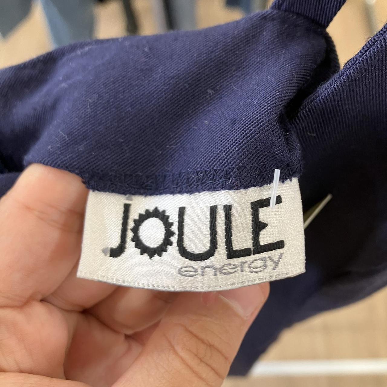 Navy blue fabric with a 'Joule Energy' label held by a hand