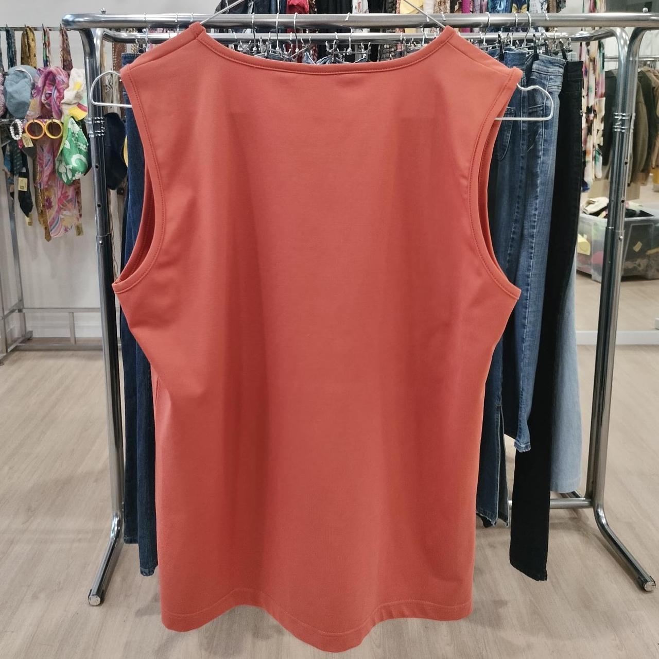 Red sleeveless shirt on a rack with clothes in the background